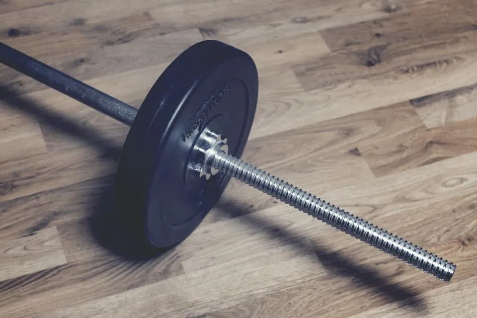 Barra con discos sobre piso de madera